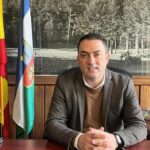 Alcalde en un despacho sobre un fondo de un cuadro y unas banderas