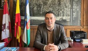 Alcalde en un despacho sobre un fondo de un cuadro y unas banderas