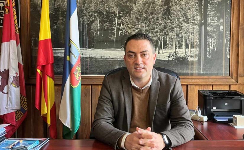 Alcalde en un despacho sobre un fondo de un cuadro y unas banderas